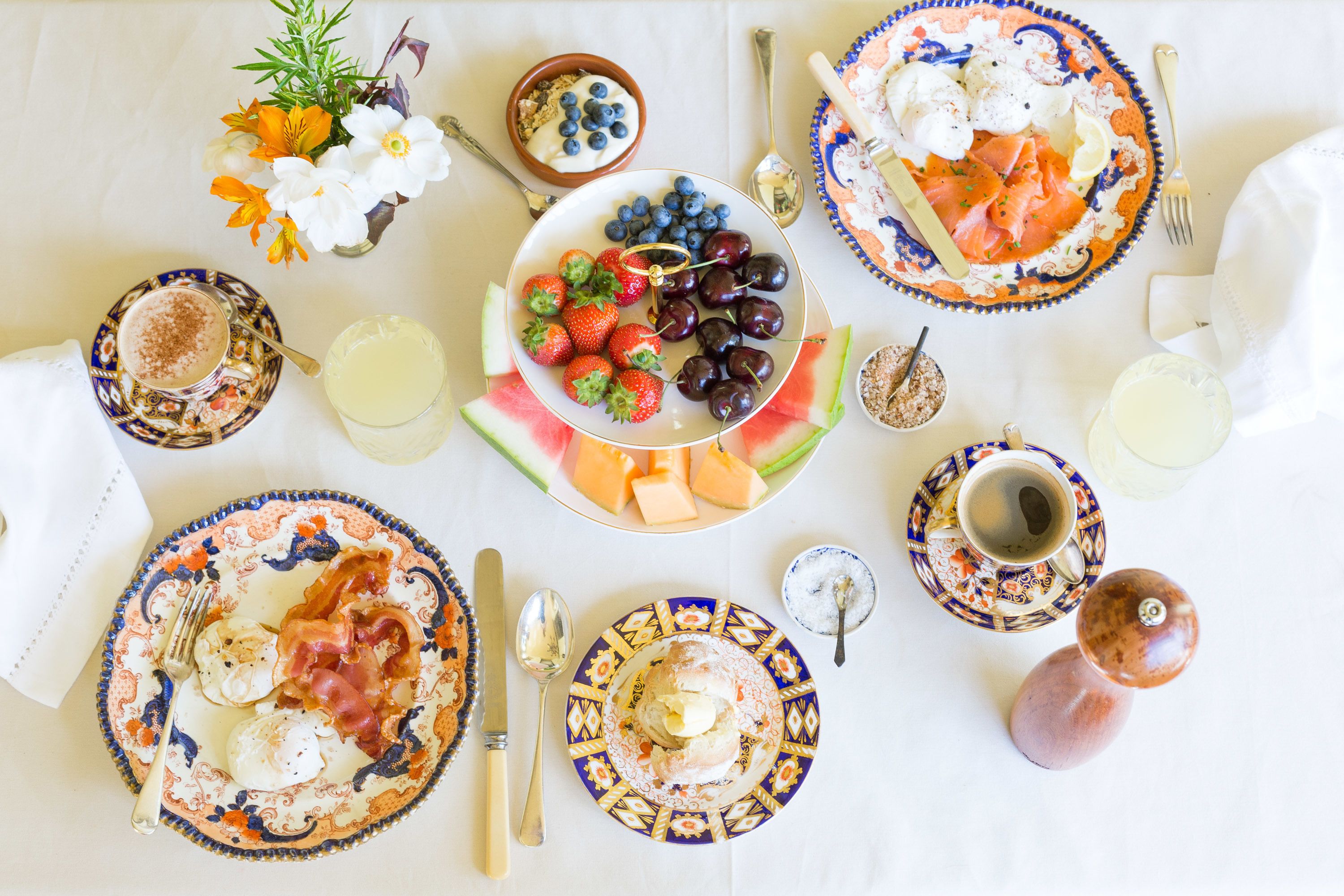 Ein gedeckter Frühstückstisch mit Speisen, einer Blumenvase und verschiedenen Frühstücksartikeln.
