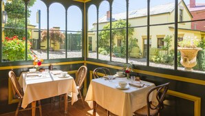 A conservatory with two tables set for dining, surrounded by wooden chairs. - Corinda Contemporary (Glebe)