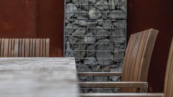 A wooden table and chairs with a stone wall in the background.