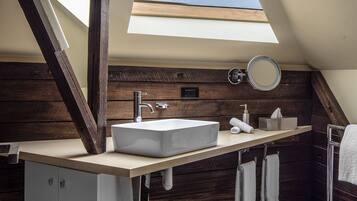 Ein modernes Badezimmer mit Oberlicht, einem großzügigen Waschbecken und Holzvertäfelung.