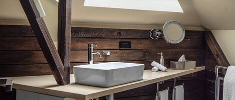 A modern bathroom with a skylight, a large sink, and wooden paneling.