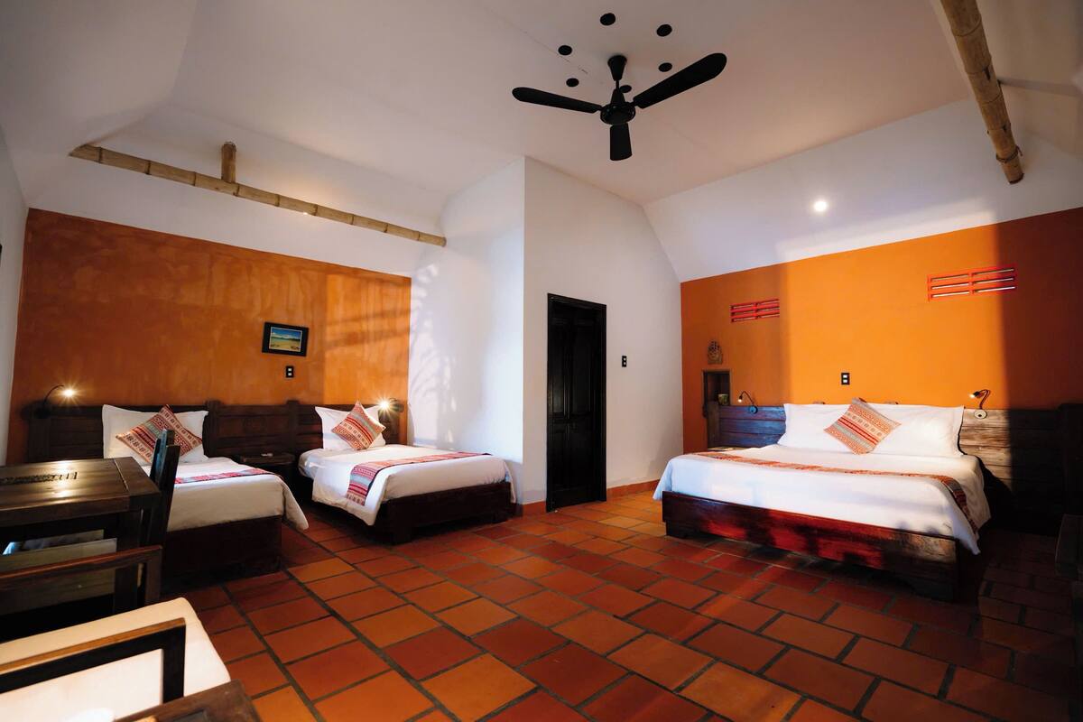 A hotel room with two beds, a wooden headboard, a ceiling fan, and a tiled floor.