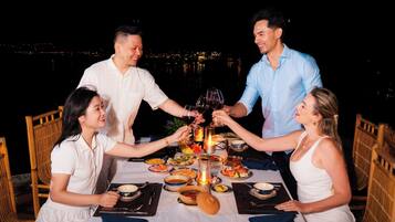 A group of people toasting at a dinner table with a view of the city at night.
