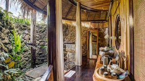 A traditional bamboo structure with a stone wall and a wooden bench.