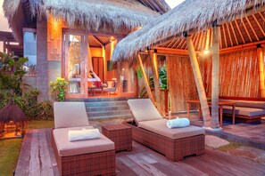 Un resort con sillones de mimbre, una estructura de techo de paja y una terraza de madera.