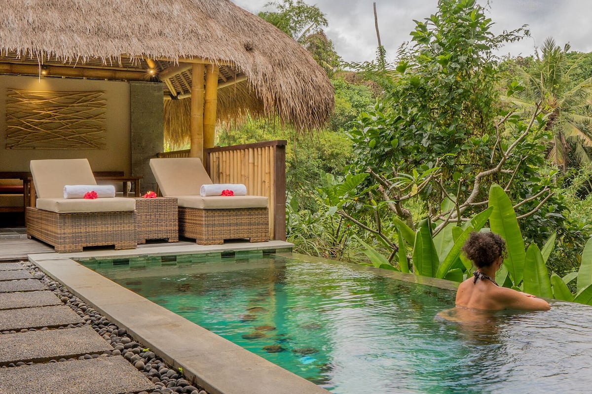 A pool area with lounge chairs and a thatched-roof structure.