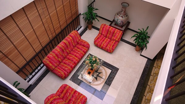 A spacious lobby with a high ceiling, a central coffee table with a vase, and a staircase on the right.