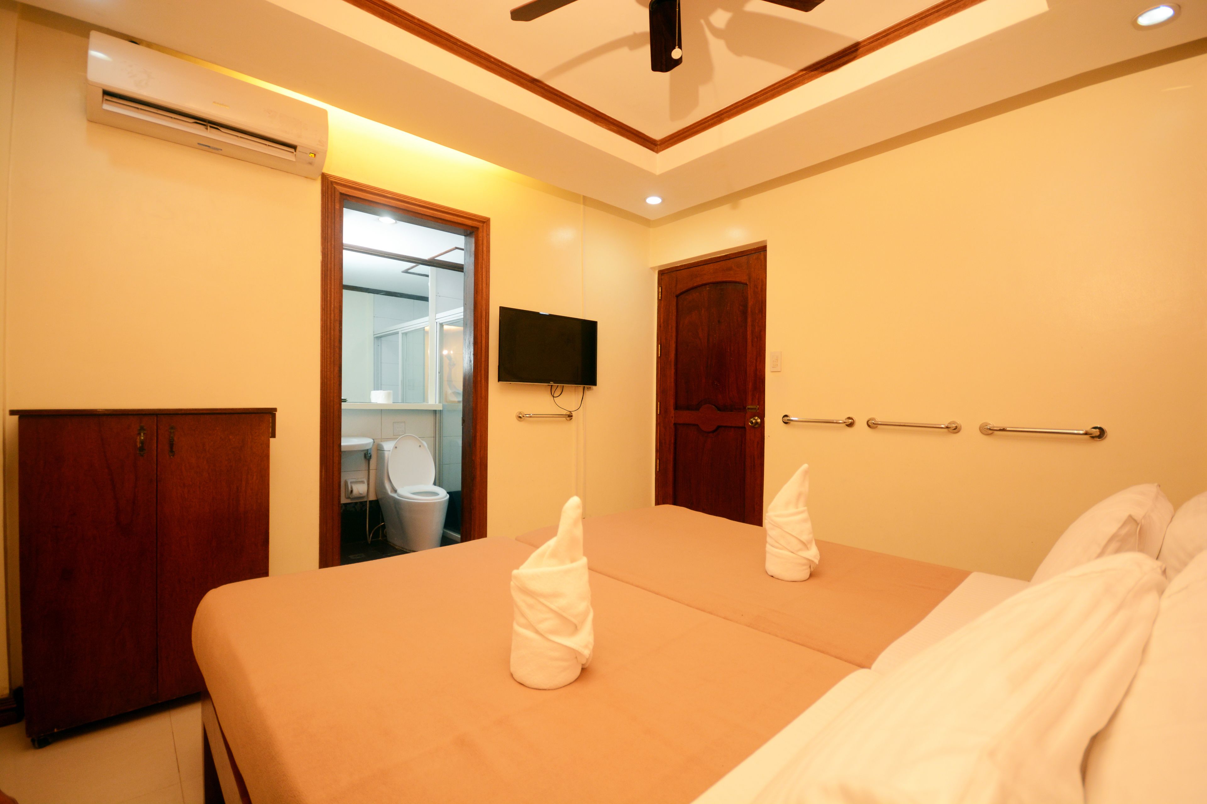 Ein Hotelzimmer mit Bett, Schrank, Fernseher und Klimaanlage.