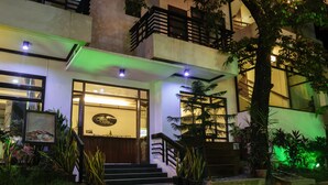 Entrada de un hotel con una escalera, una recepción y plantas en macetas.