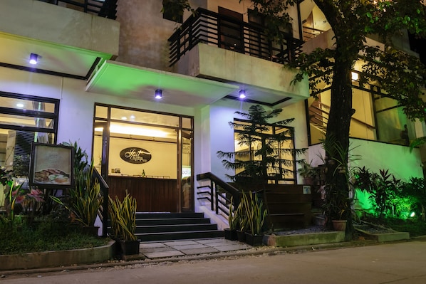 Entrada de un hotel con una escalera, una recepción y plantas en macetas.