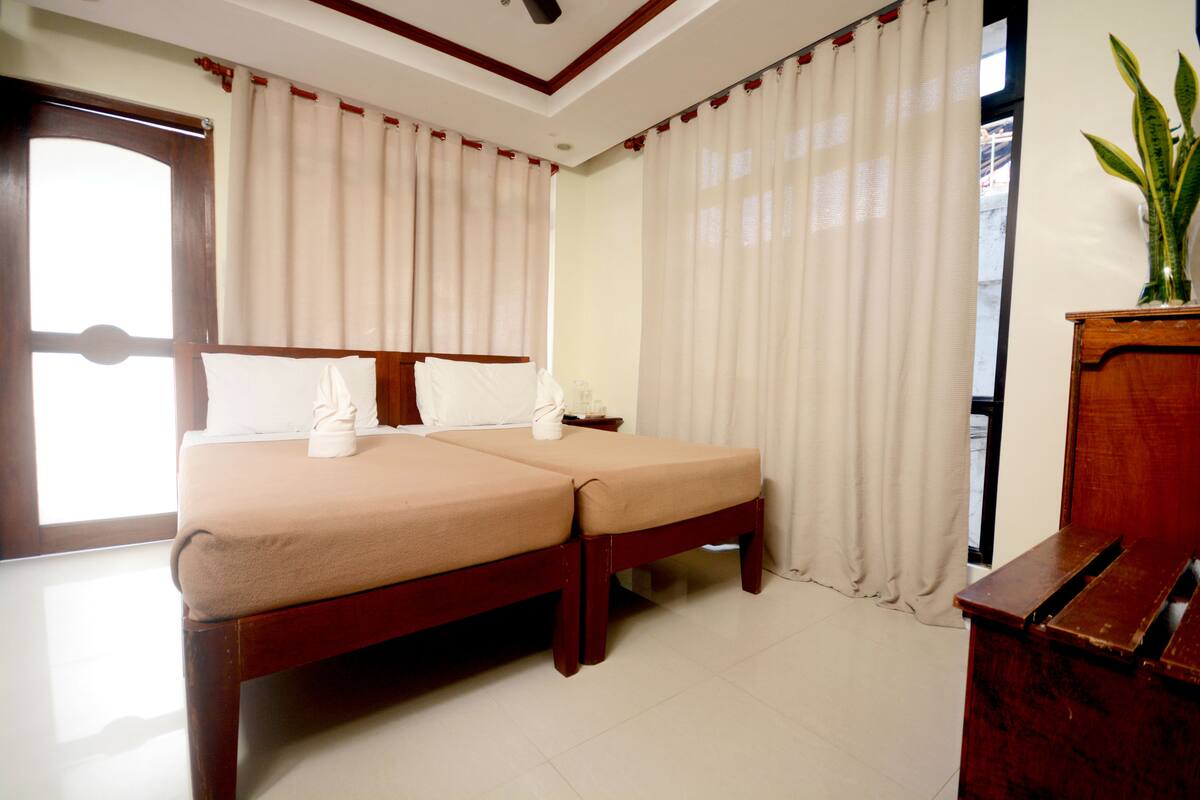 A double bed with a wooden frame, a bedside table, and a potted plant.