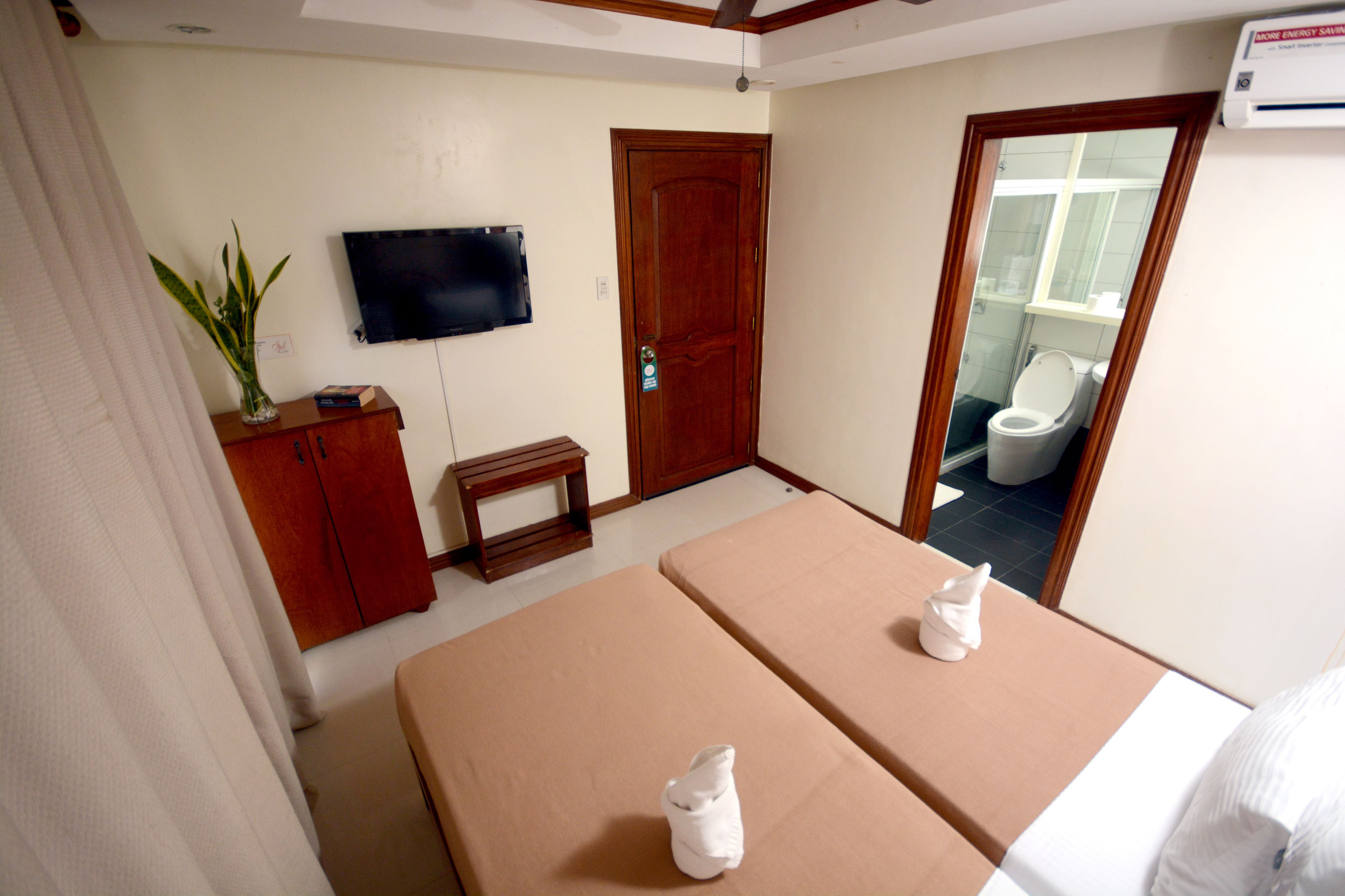 A room with two massage tables, a wooden cabinet, a television, and a door leading to a bathroom.