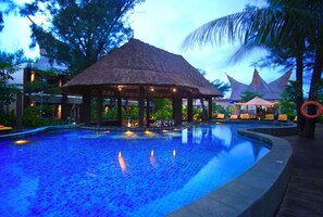A pool area with a thatched-roof gazebo, lounge chairs, and a palm tree. - Aston Sunset Beach Resort Gili Trawangan Lombok (Gili Trawangan)