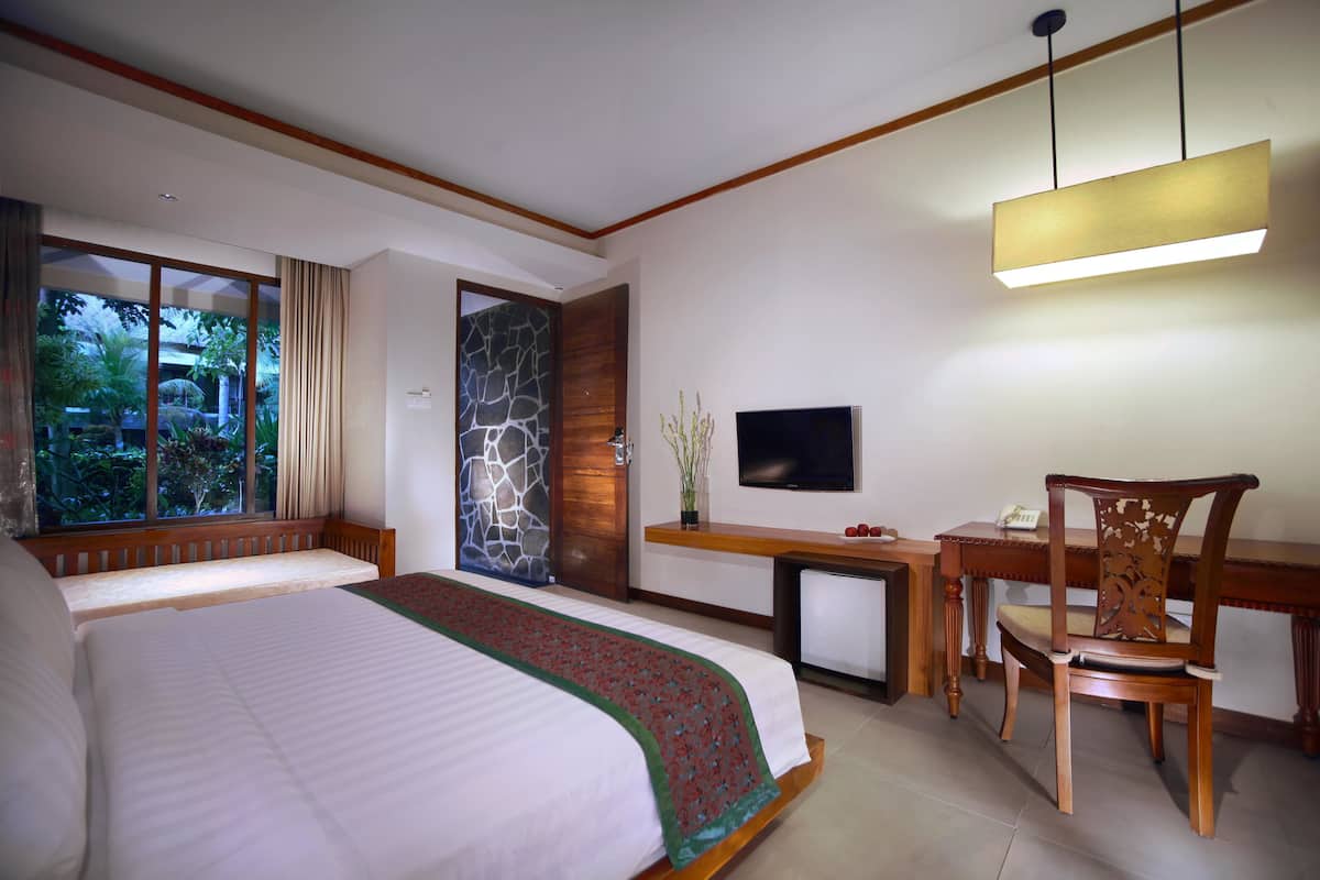Une chambre d’hôtel avec un grand lit, un bureau avec une chaise, une télévision et une fenêtre avec des rideaux.