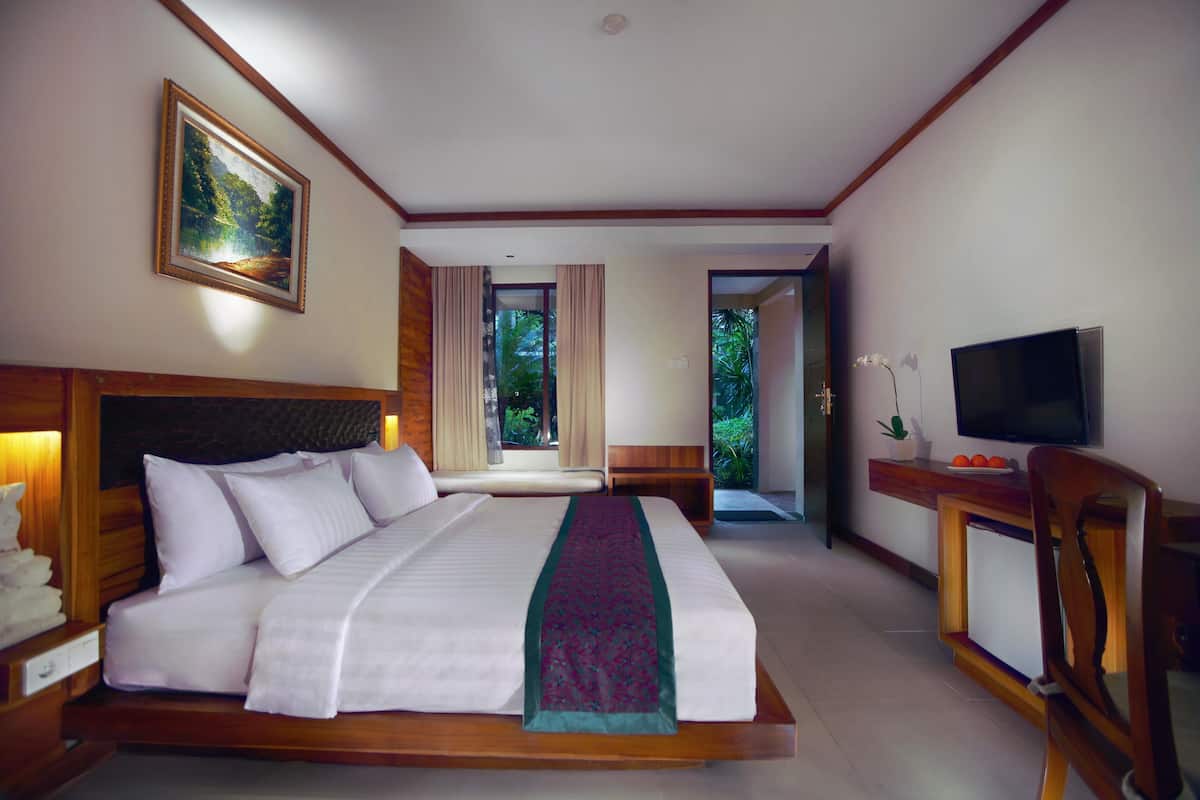 Une chambre d’hôtel avec un grand lit, une télévision, un bureau et une fenêtre avec des rideaux.