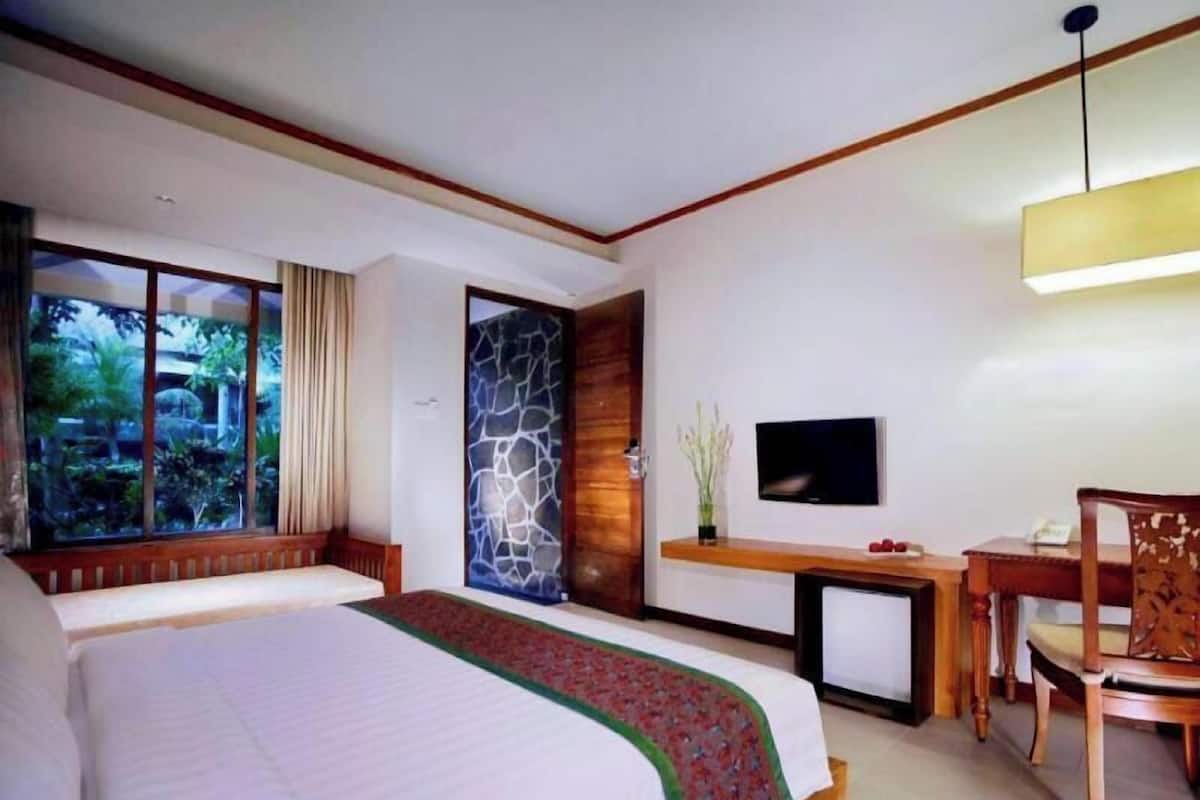 Une chambre d’hôtel avec un grand lit, une télévision, un bureau et une chaise.