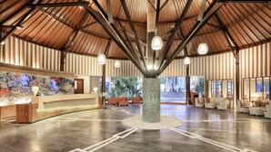 A spacious lobby with a high ceiling, a reception desk, seating area, and a decorative column.