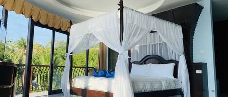 Un dormitorio con cama con dosel, ventanas amplias con cortinas y un balcón con vista a palmeras.