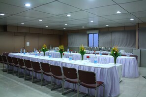 Uma sala de conferências com mesas compridas, cadeiras e arranjos florais.