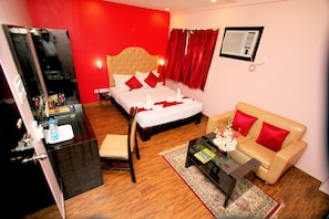 Quarto de hotel com cama, sofá, escrivaninha e espelho.