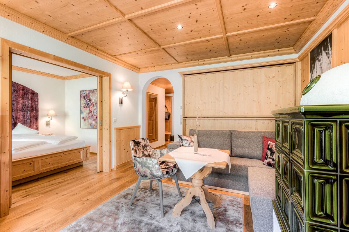 Una habitación acogedora con techo de madera, una cama, un sofá, una mesa y un armario verde.