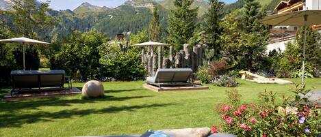 Un jardín con mobiliario exterior, una roca grande y vistas a la montaña.