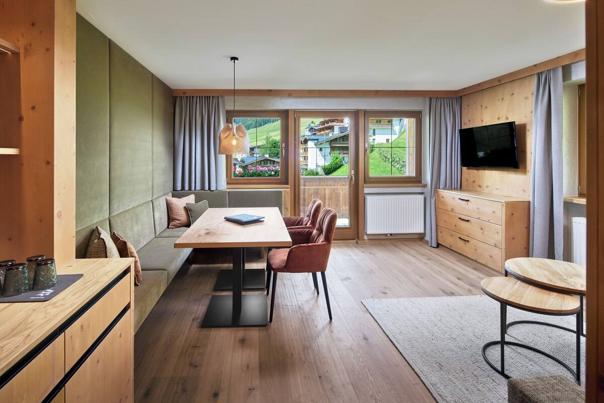 Una cocina moderna con armarios de madera, una mesa de comedor y un televisor montado en la pared.