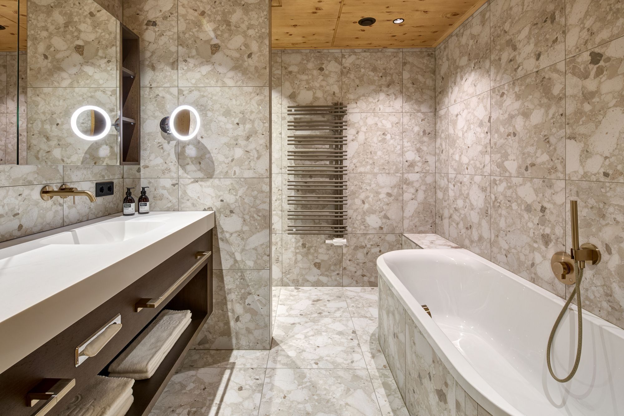 A modern bathroom with a freestanding bathtub, a vanity with a mirror and lights, and a towel rack.