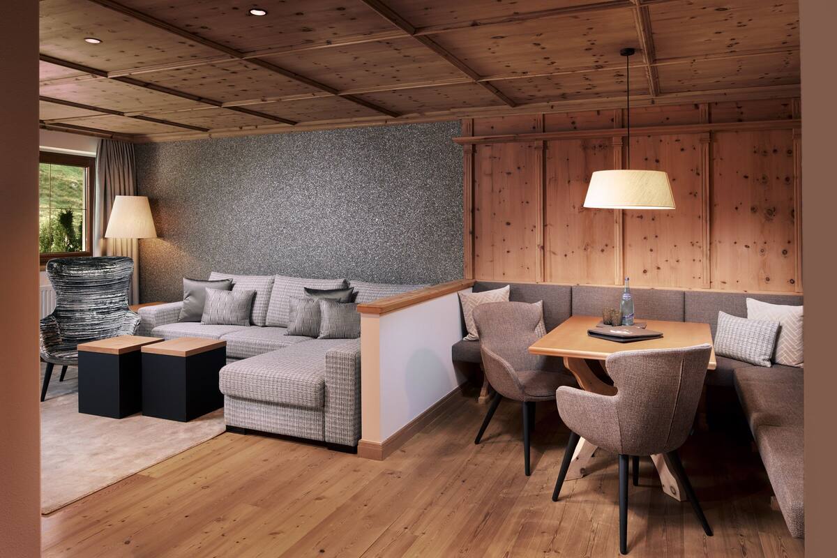 Una sala de estar moderna con pared gris con textura, techo de madera y un conjunto de sofás.