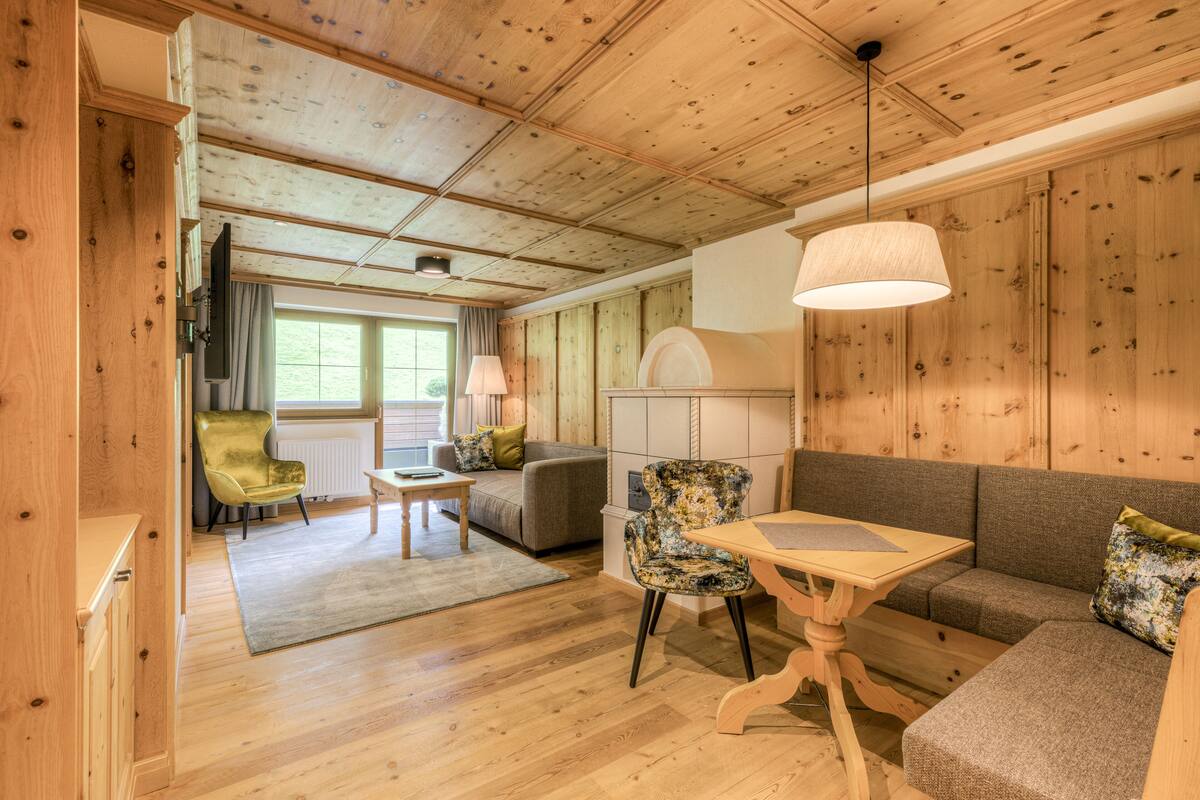 Una habitación acogedora con paredes y suelos de madera, un sofá, una silla, una mesita y una lámpara.