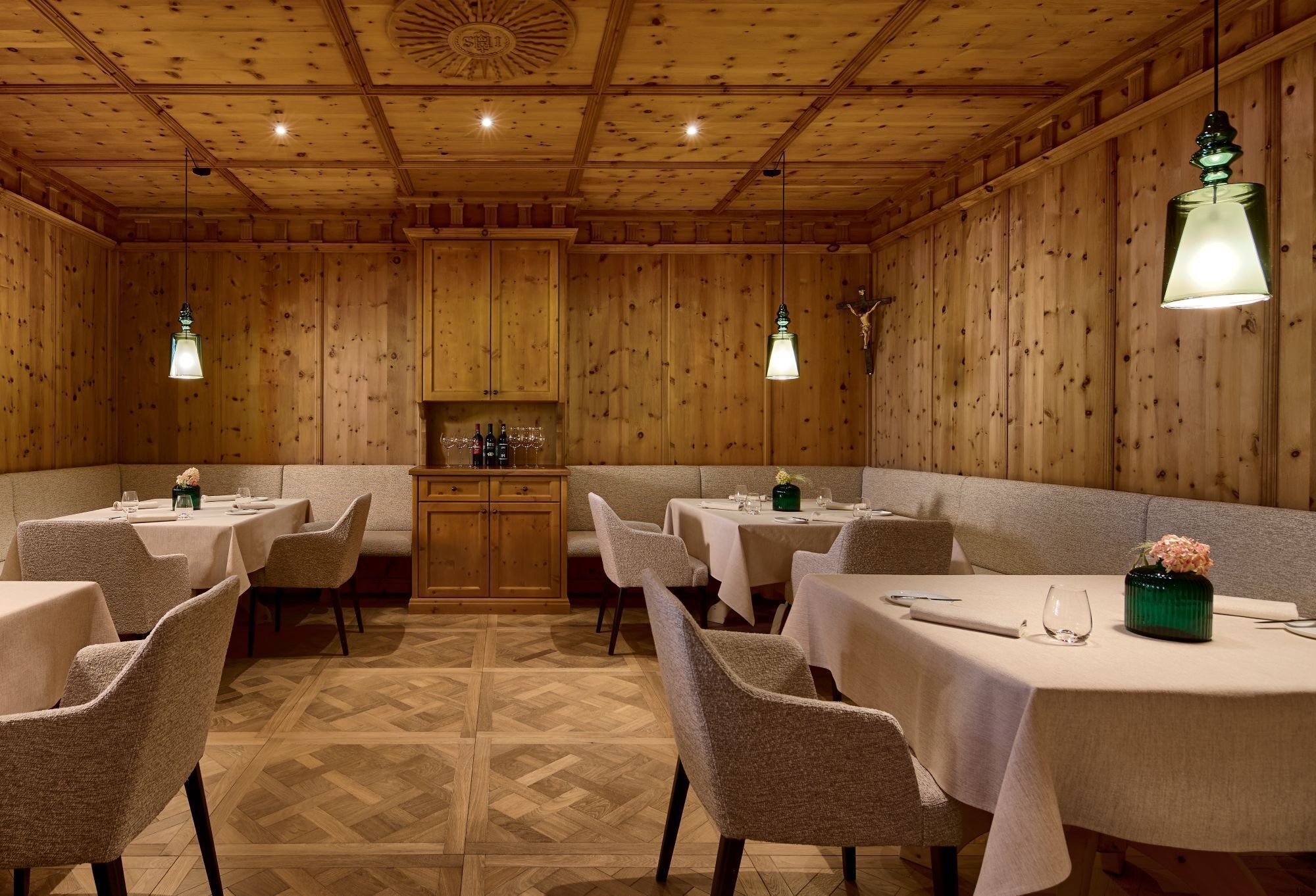 Un restaurante con paredes de paneles de madera, varias mesas con sillas y lámparas colgantes.