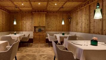 Un restaurante con paredes de paneles de madera, varias mesas con sillas y lámparas colgantes.