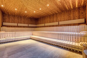 A wooden interior with a long bench along the wall, recessed lighting, and a tiled floor.