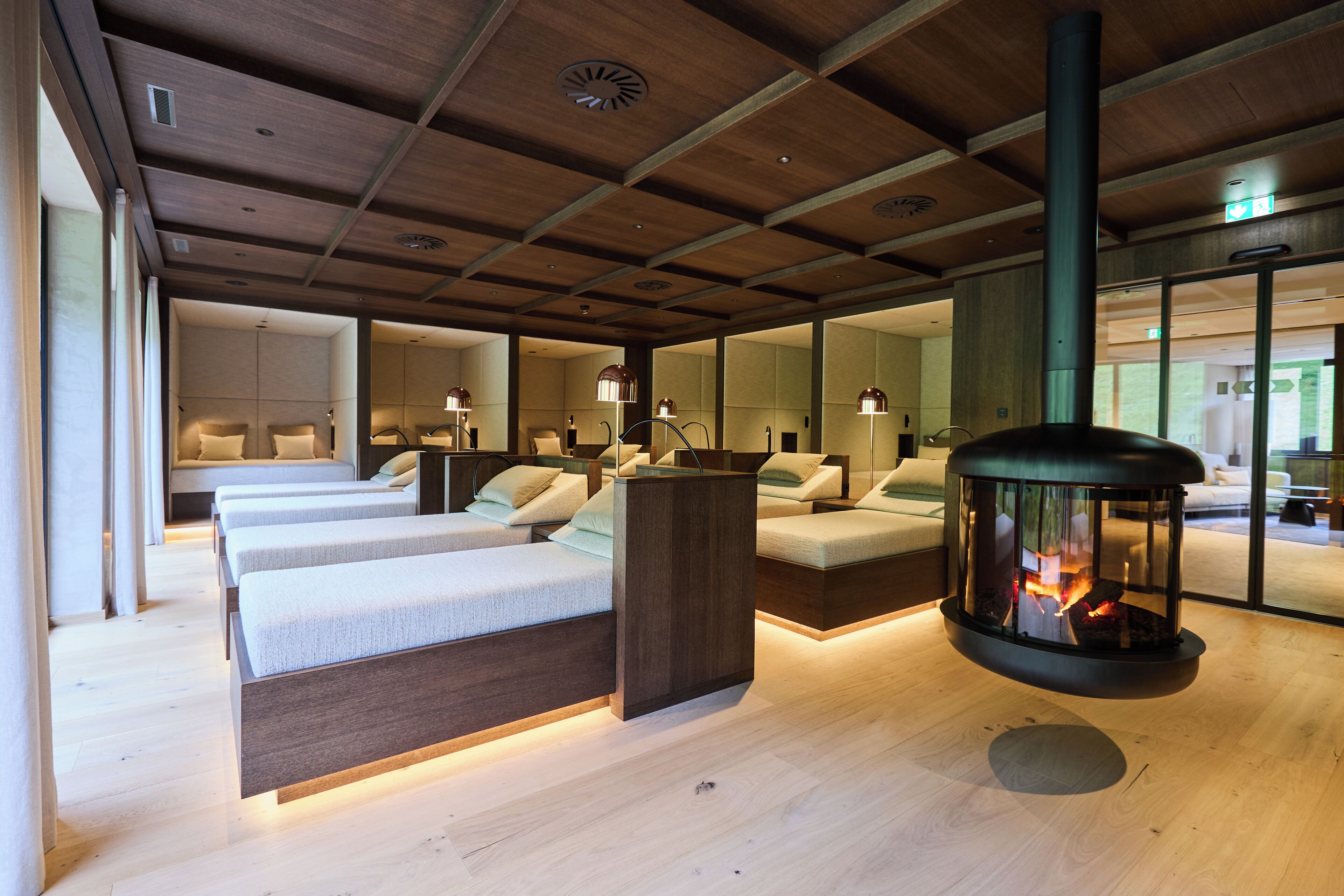 A modern hotel room with a wooden ceiling, a fireplace, and a large mirror.
