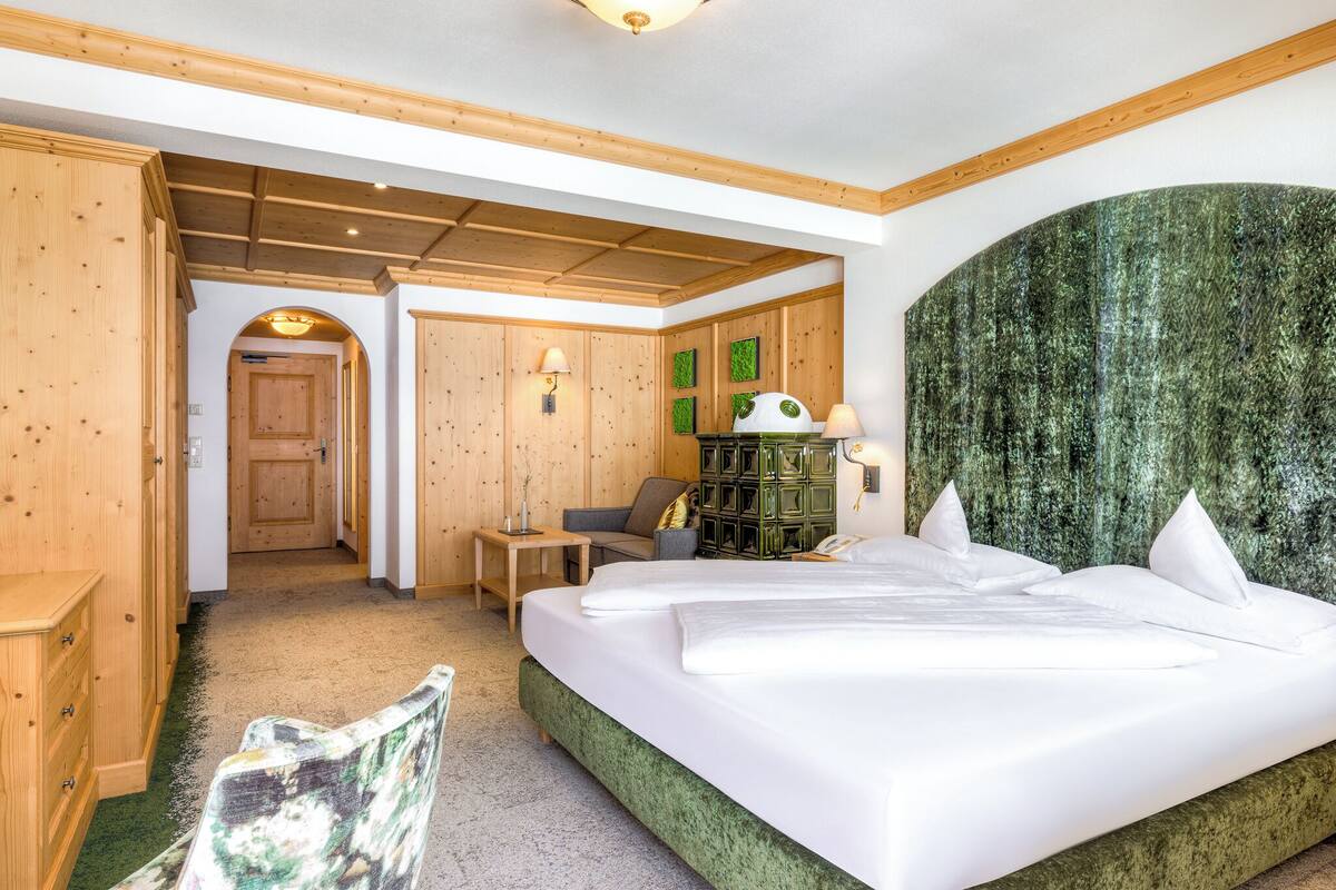 Una habitación de hotel con una cama grande, muebles de madera, una pared de acento verde y techo de madera.
