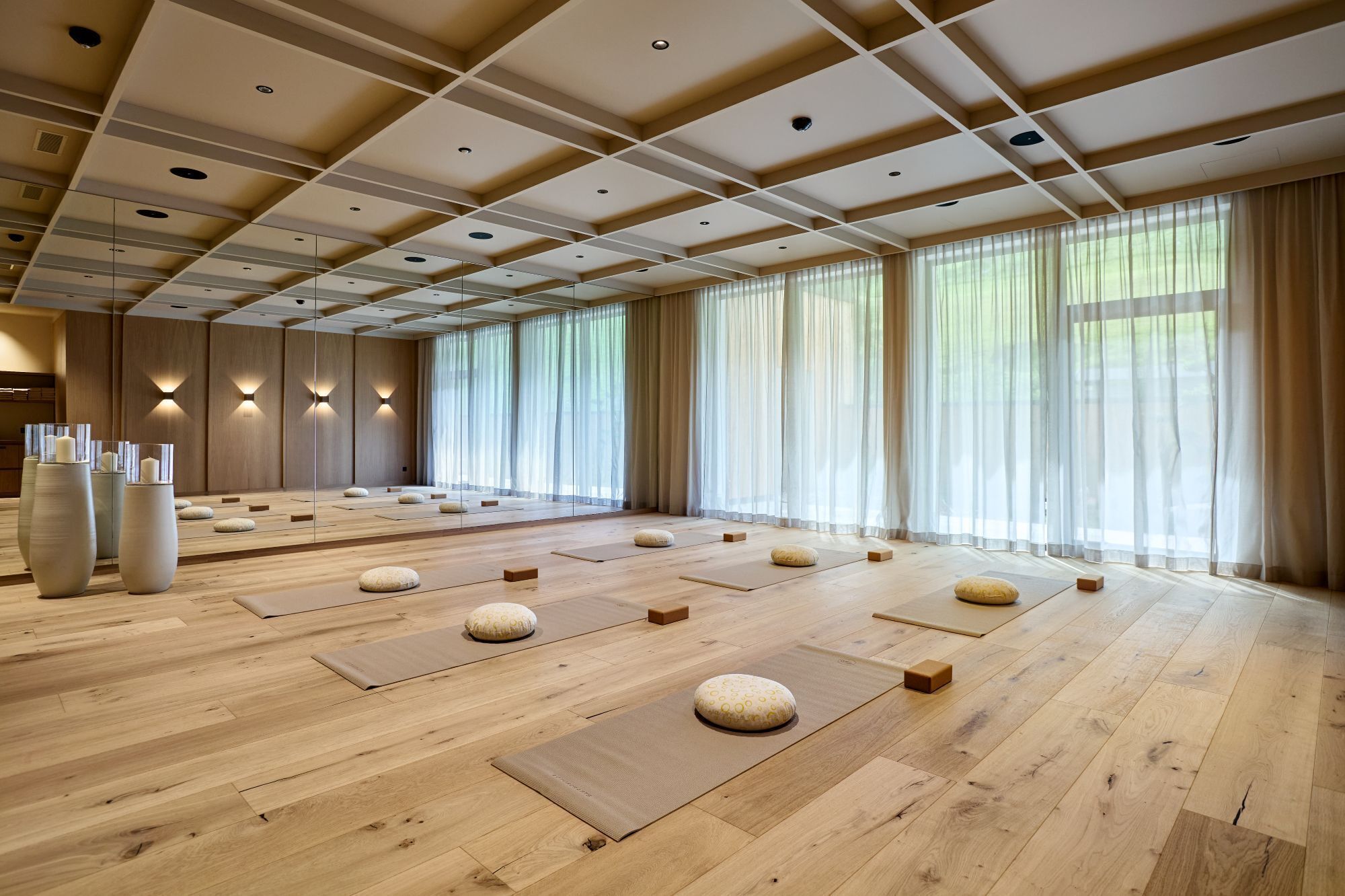 A spacious room with wooden flooring, tatami mats, and cushions.