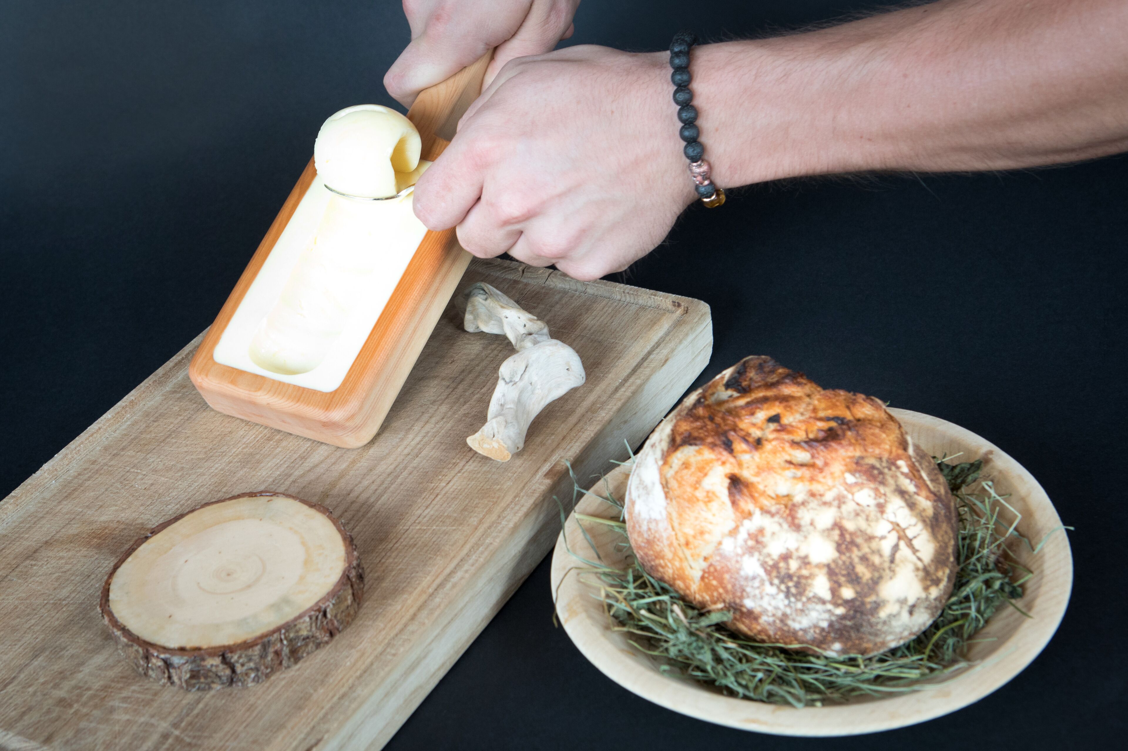 A person slicing a baguette on a wooden cutting board with a knife.