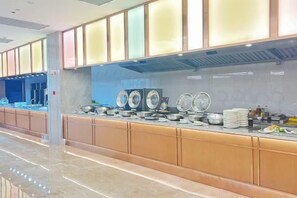 Un área de bufé con una mesa larga, varias estaciones de servicio y una variedad de platos.