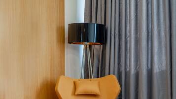 Una habitación moderna con un panel de pared de madera, un tapete redondo y una silla naranja original, además de una lámpara de pie.