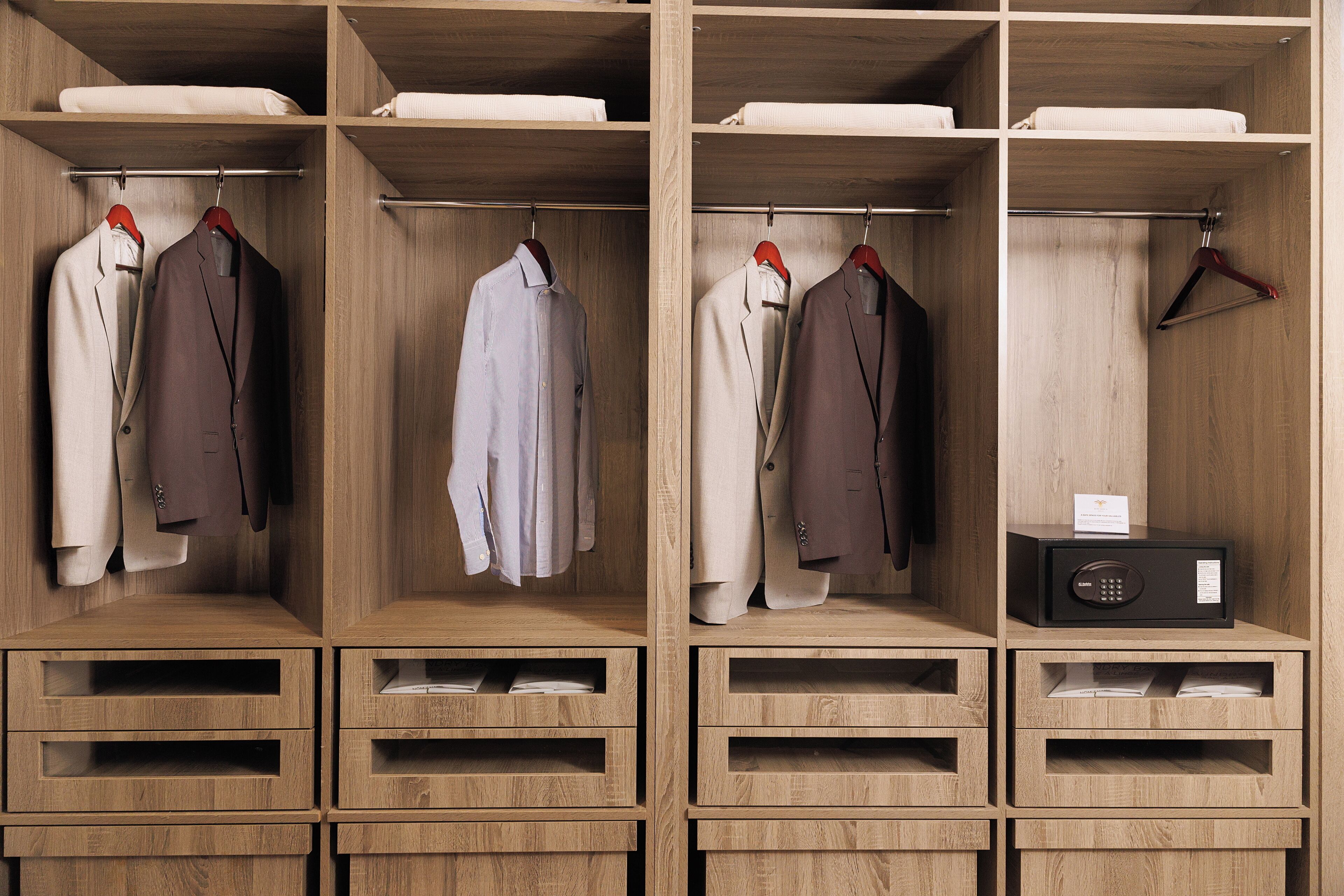Ein hölzerner Kleiderschrank mit mehreren Fächern, darunter Kleiderstangen für Anzüge und Hemden sowie Schubladen für zusätzlichen Stauraum.