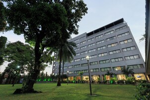 A modern building with multiple floors, surrounded by a well-maintained grassy area with trees and street lamps.