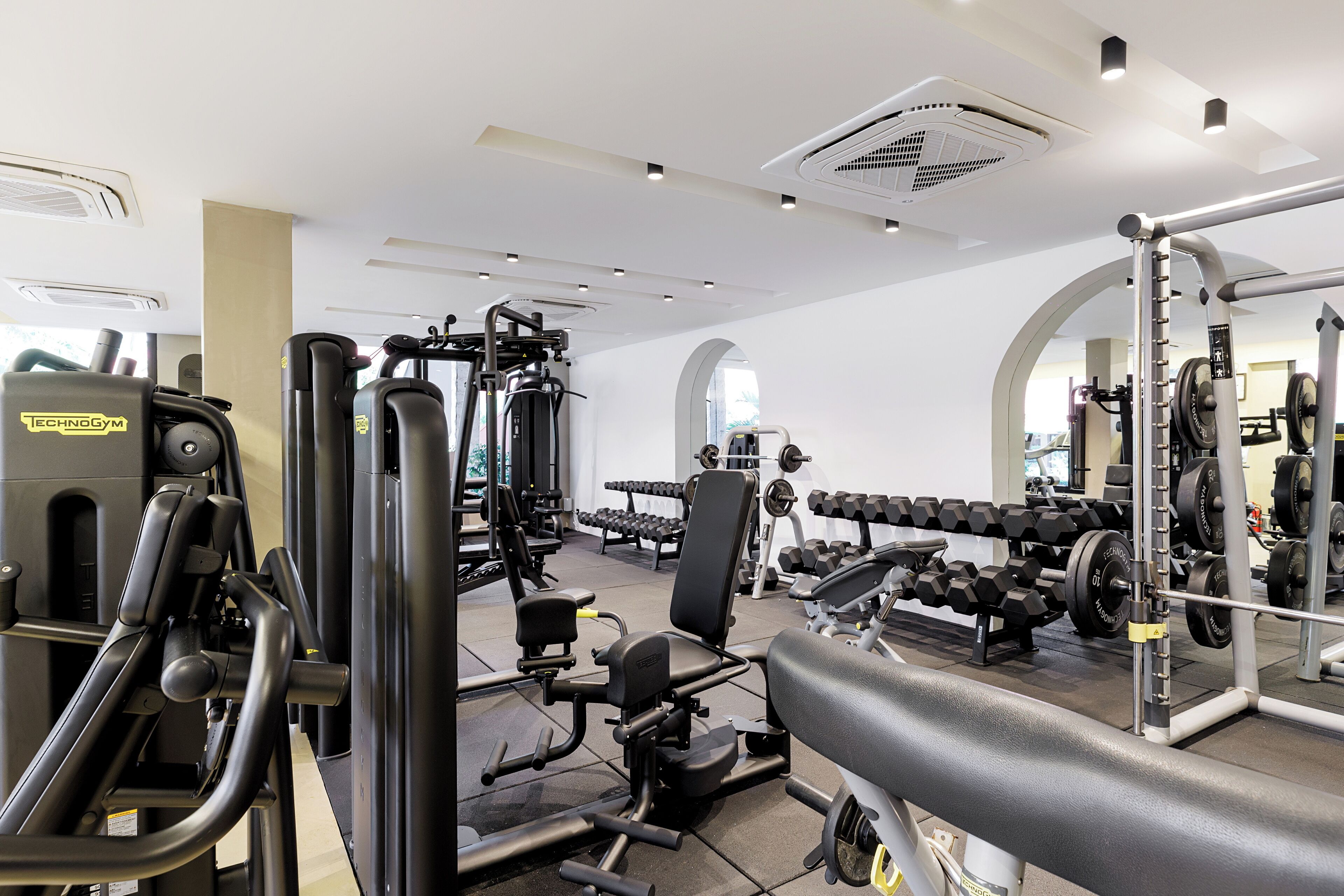 A modern gym with various exercise equipment, mirrors, and ample lighting.