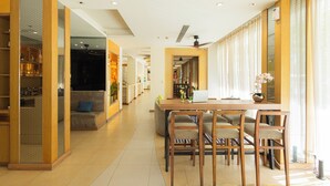 A spacious living area with a dining table, chairs, and a sofa. There is a kitchen area in the background with a refrigerator and a sink. - ASHLEE Plaza Patong Hotel & Spa (Patong)