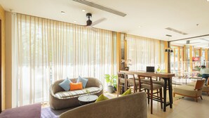 A spacious living area with a sofa, armchairs, a dining table, and a ceiling fan. - ASHLEE Plaza Patong Hotel & Spa (Patong)