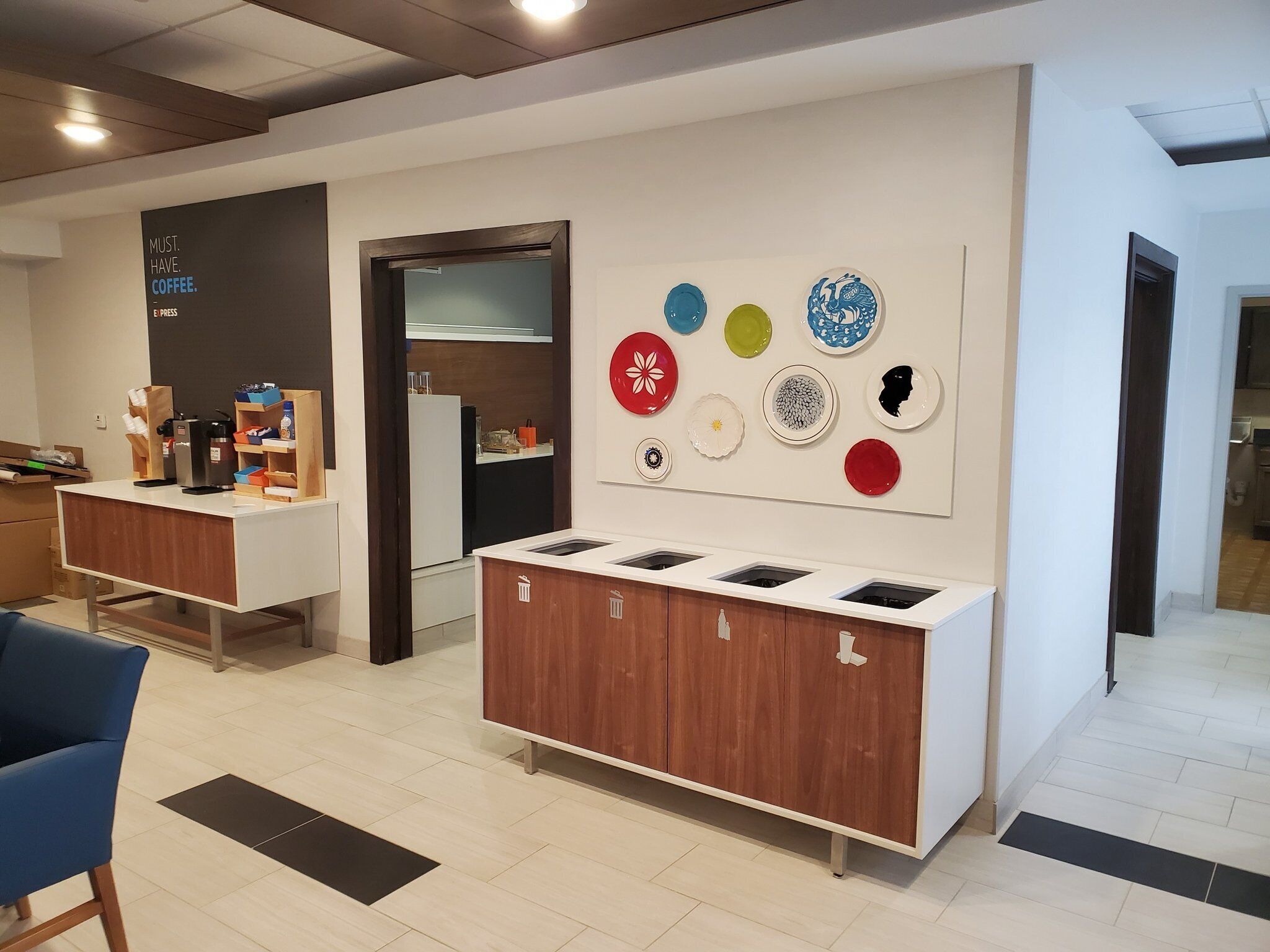 A modern coffee shop interior with a counter, seating area, and a wall display of colorful plates.