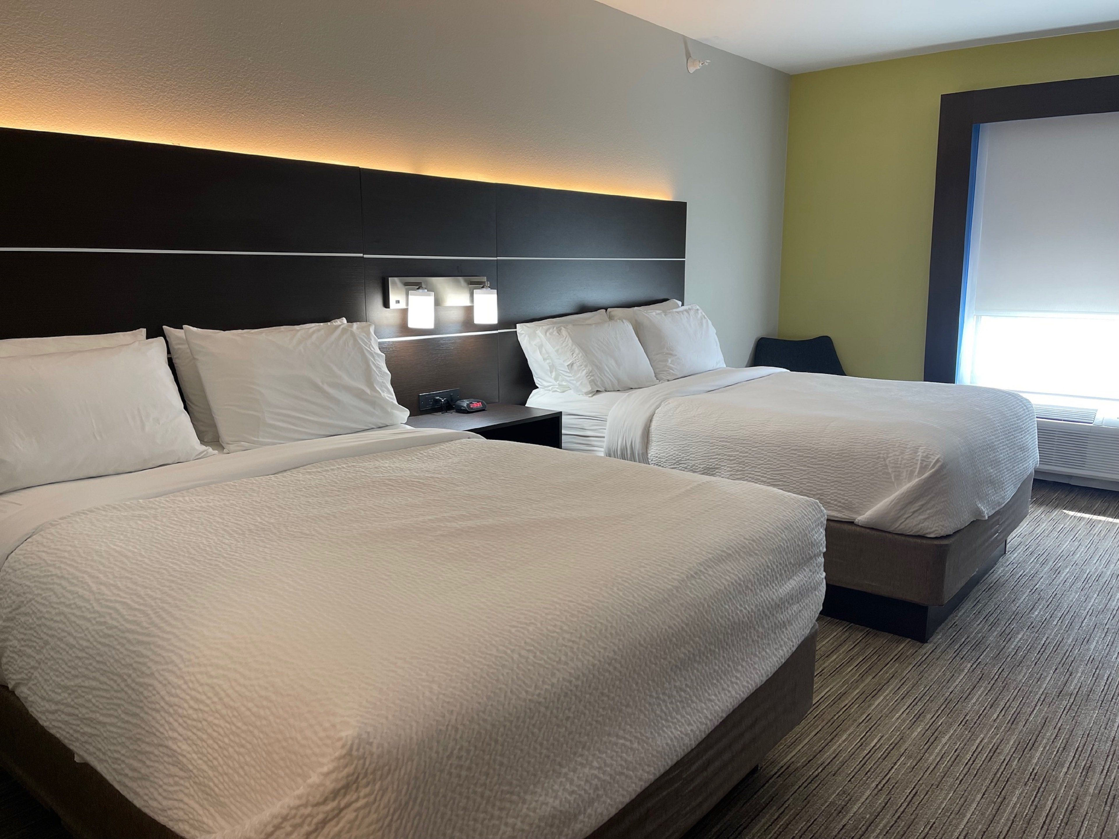 Ein Hotelzimmer mit zwei Betten, einem Nachttisch und einer wandmontierten Lampe.