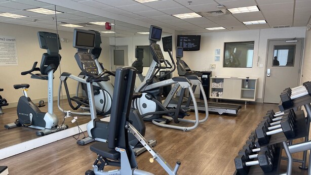 Une salle de sport équipée de divers appareils d’exercice, notamment des tapis de course, des vélos d’appartement et des appareils de musculation.