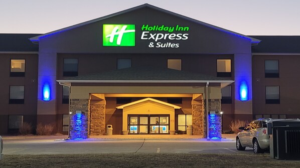 A Holiday Inn Express & Suites building with a prominent green and white logo, a covered entrance, and blue lighting accents. - Holiday Inn Express & Suites Junction City by IHG (Junction City)