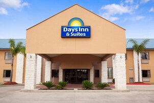 Edificio de Days Inn & Suites con un cartel llamativo, techo plano y fachada simétrica con pilares de piedra y palmeras.