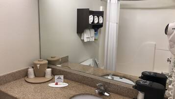 A hotel bathroom with a granite countertop, a sink, a mirror, a towel rack, a shower curtain, and a hairdryer.